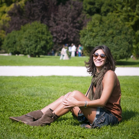 beautiful girl with scarf and sunglasses on the lawn in autumnの写真素材