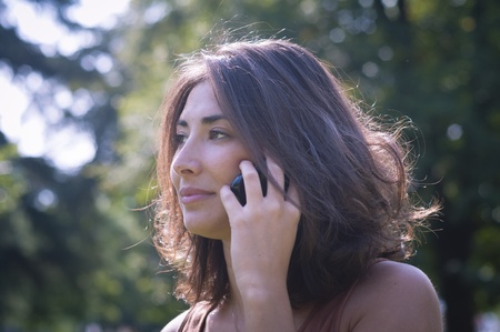 beautiful girl talking on the phone on the lawn in autumnの写真素材