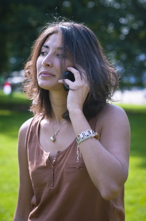 beautiful girl talking on the phone on the lawn in autumnの写真素材