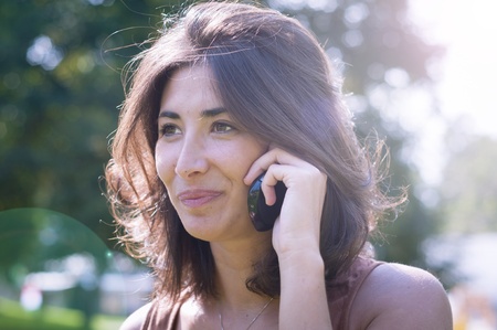 beautiful girl talking on the phone on the lawn in autumnの写真素材