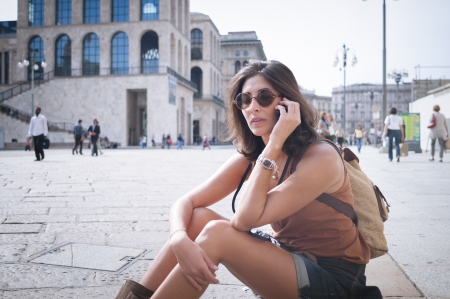 beautiful girl talking on the phone on the lawn in autumnの写真素材