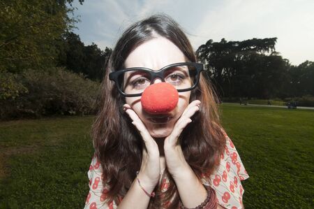 sad clown girl with red nose at the park in milanの写真素材