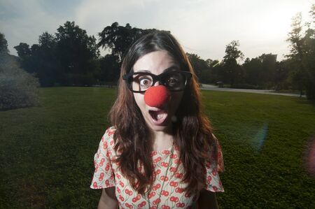 surprised clown girl with red nose at the park in milanの写真素材