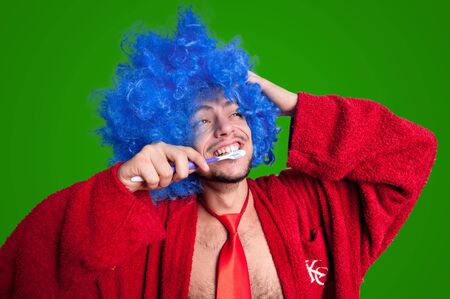 crazy guy with a toothbrush, wig and bathrobe singing on green backgroundの写真素材