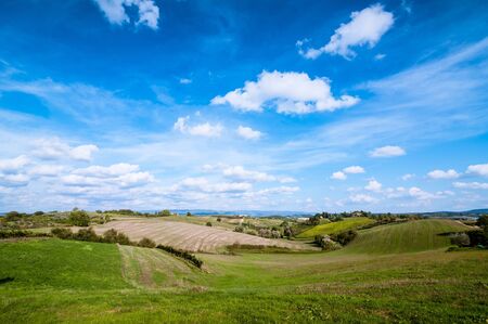 Tuscan countryside landscape with blue sky, clouds and meadowsの写真素材