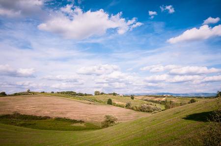 Tuscan countryside landscape with blue sky, clouds and meadowsの写真素材