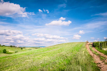 Tuscan countryside landscape with blue sky, clouds and meadowsの写真素材