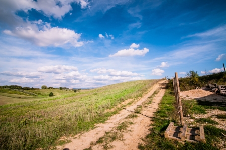Tuscan countryside landscape with blue sky, clouds and meadowsの写真素材