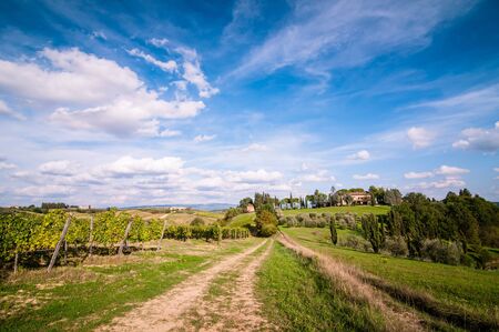 Tuscan countryside landscape with blue sky, clouds and meadowsの写真素材