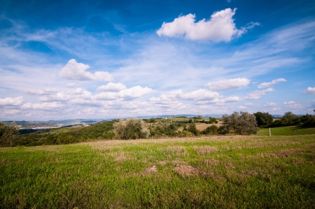 Tuscan countryside landscape with blue sky, clouds and meadowsの写真素材