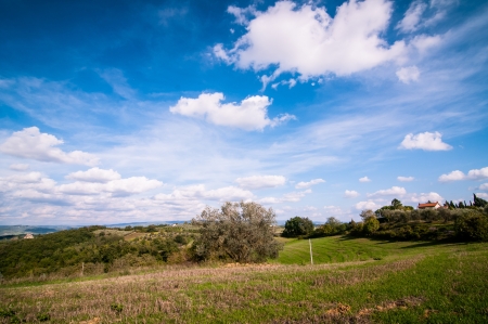 Tuscan countryside landscape with blue sky, clouds and meadowsの写真素材