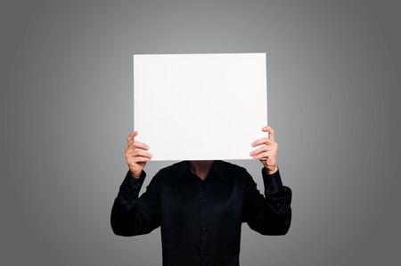 man with black shirt holding blank white board on gray backgroundの写真素材