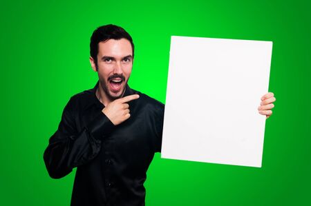 man with mustache and black jacket holding blank white board on green backgroundの写真素材