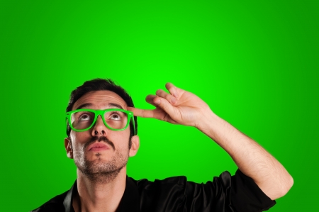 thoughtful man with green eyeglasses and green backgroundの写真素材