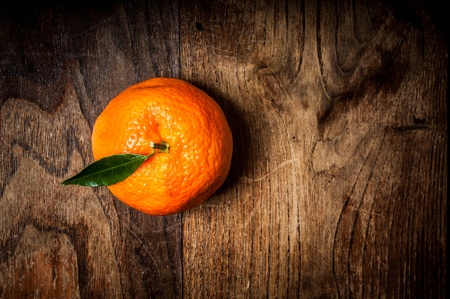 mandarin with leaf on brown woodの写真素材