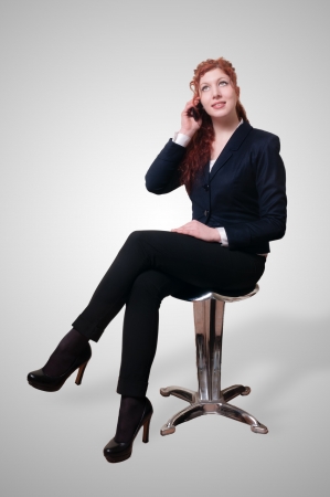 Sitting success business woman with long red hair on white backgroundの写真素材
