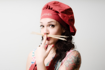 beautiful tattooed pinup cook girl with spaghetti on gray backgroundの写真素材