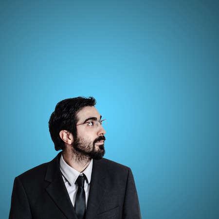 bearded business man looking up on blue backgroundの写真素材