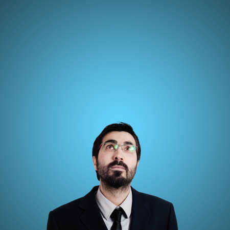 bearded business man looking up on blue backgroundの写真素材