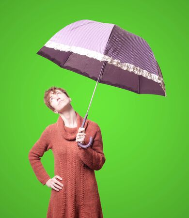beautiful woman with sweater and umbrella on green backgroundの写真素材