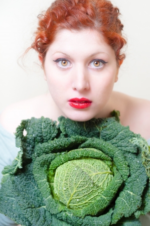 beautiful red hair and lips girl with savoy cabbage on white backgroundの写真素材