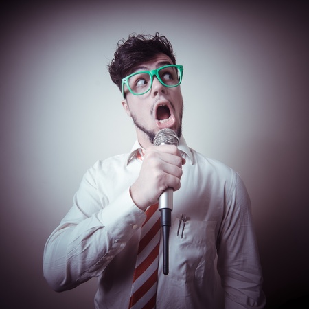 funny stylish businessman singing on gray backgroundの写真素材