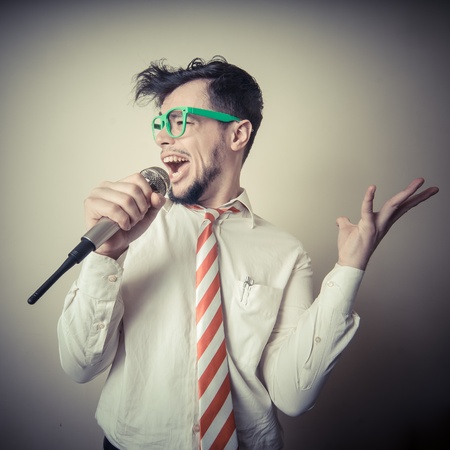 funny stylish businessman singing on gray backgroundの写真素材