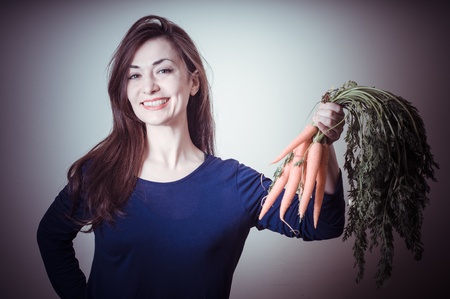 beautiful woman with carrots on gray backgroundの写真素材