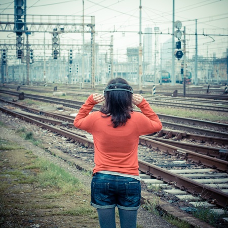 Beautiful stylish woman listening to music in railway