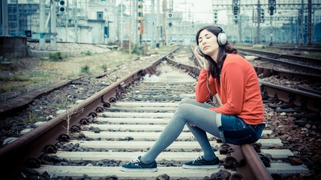 Beautiful stylish woman listening to music in railwayの写真素材
