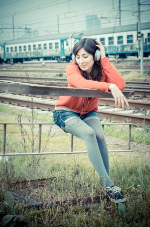 Beautiful stylish woman listening to music in railwayの写真素材
