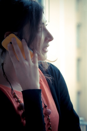 beautiful woman at home at the phone near windowの写真素材