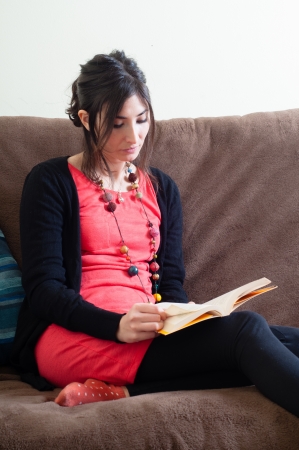 woman at home reading book on couchの写真素材