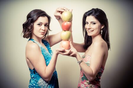 two beautiful girls with apples on gray backgroundの写真素材