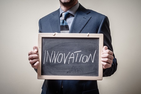 businessman holding blackboard written innovation on gray backgroundの写真素材