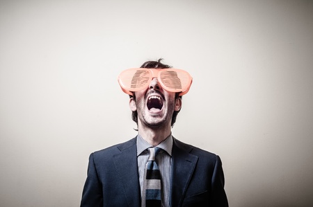 funny businessman with big orange glasses on gray backgroundの写真素材