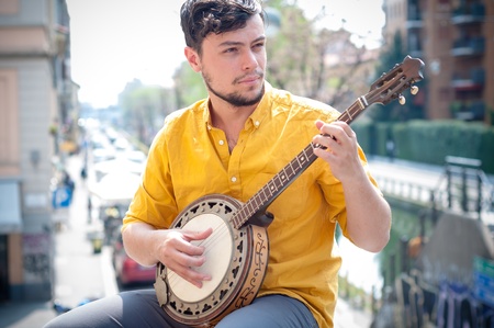hipster young man playing banjo in the cityの写真素材