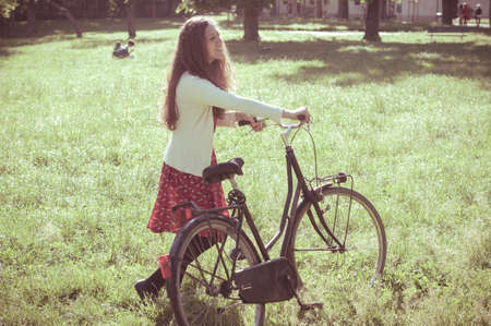 vintage eastern hipster woman with bike in the parkの写真素材