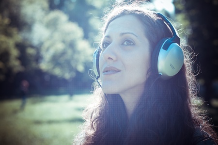 vintage hipster eastern woman with headphones in the park