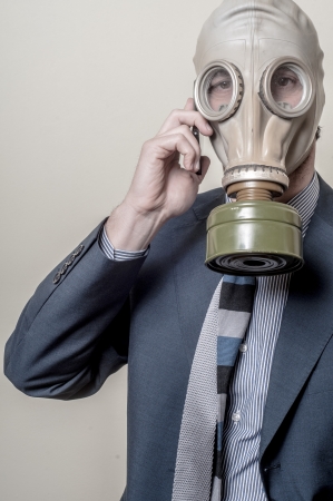 businessman with gas mask with phone on gray backgroundの写真素材
