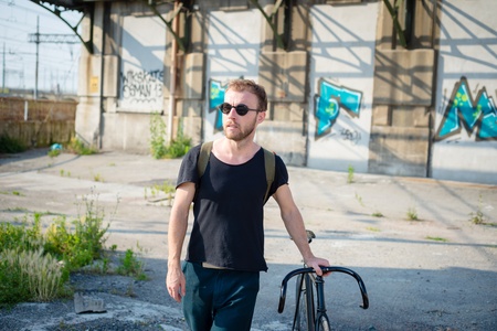 hipster modern stylish blonde man with bike in daily lifeの写真素材