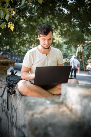 young stylish man using notebook at the parkの写真素材