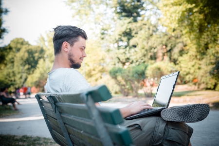 young stylish man using notebook at the parkの写真素材