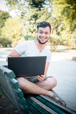 young stylish man using notebook at the parkの写真素材