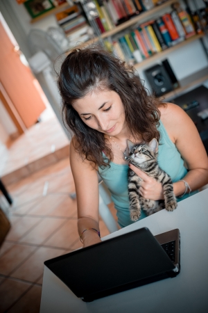 woman using notebook with cat at homeの写真素材