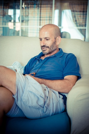 middle age man using phone at homeの写真素材