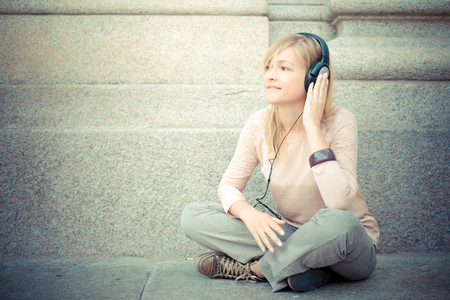 beautiful blonde woman listening to music in the cityの写真素材
