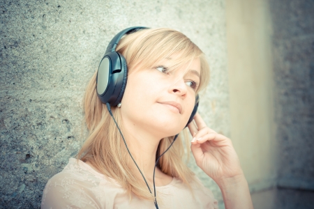 beautiful blonde woman listening to music in the cityの写真素材