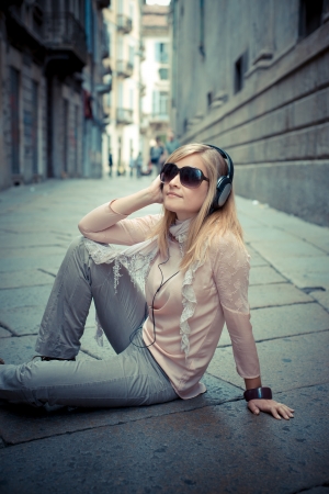 beautiful blonde woman listening to music in the cityの写真素材