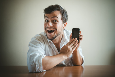 young stylish man with white shirt on the phone behind a tableの写真素材